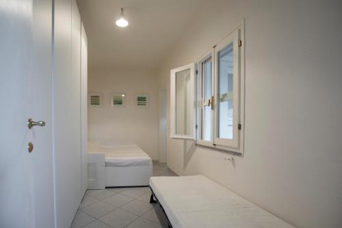 um quarto branco com 2 camas e uma janela em Casa di Cosimo by HelloElba em Portoferraio