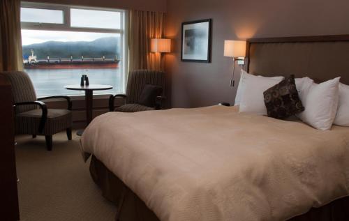 a hotel room with a large bed and a window at Inn on the Harbour in Prince Rupert