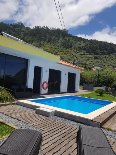 a swimming pool in front of a house at migs'place in Arco da Calheta