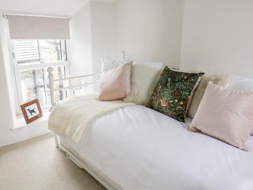 Un dormitorio con una cama blanca con almohadas y una ventana en Pine Cottage en Sedbergh