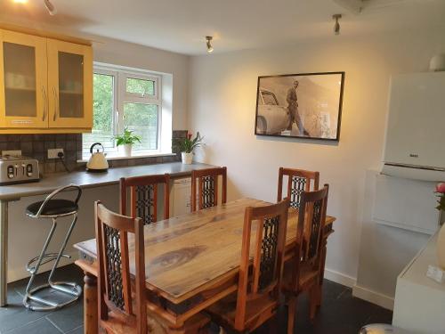 a kitchen with a wooden table and chairs in a kitchen at Stansted Lodge Guest House in Elsenham
