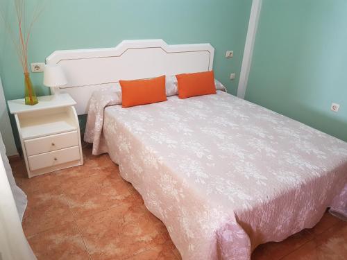 a bedroom with a white bed with an orange pillow at Apartamentos Las Salinas 2 in Caleta de Interián