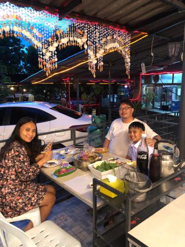 a family sitting at a table eating at a restaurant at Baan Suan Resort2345 in Ban Nong Waeng