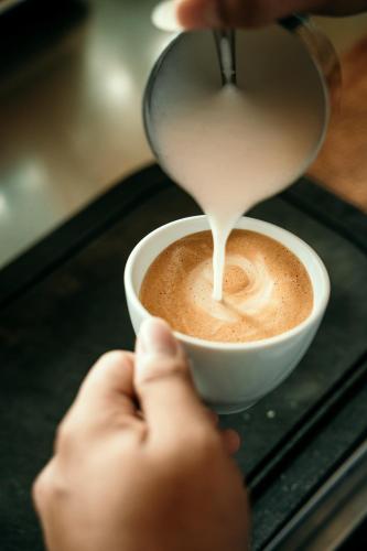 a person is pouring milk into a cup of coffee at Sand in My Shoes Beach Loft in Thong Nai Pan Noi