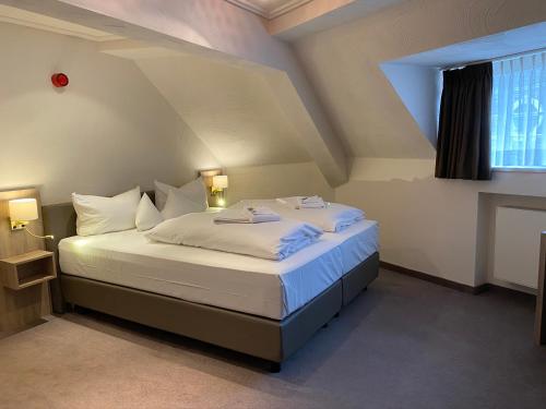 una camera da letto con un letto con lenzuola bianche e una finestra di Horchem Hotel-Restaurant-Café-Bar a Monschau
