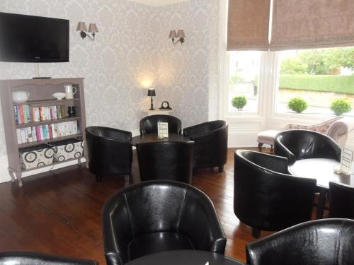 uma sala de espera com cadeiras e mesas pretas e uma televisão em Powys Lodge em Scarborough