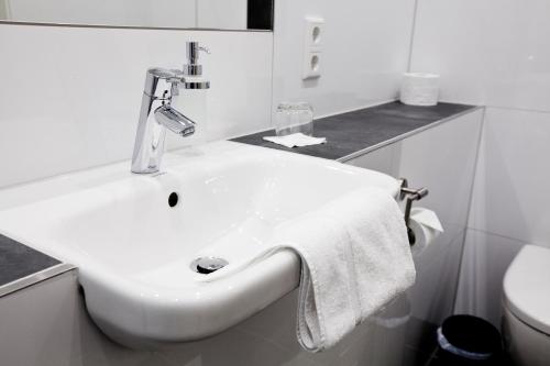 lavabo blanco en el baño con toalla en Hotel Siebenschläfer, en Alsdorf