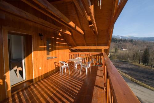 a wooden deck with two chairs and a table on it at Pension Studenov in Rokytnice nad Jizerou