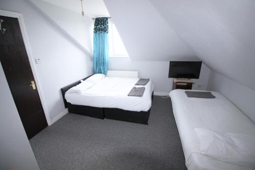 a small room with two beds and a television at Clock House Hotel - London Croydon in Croydon