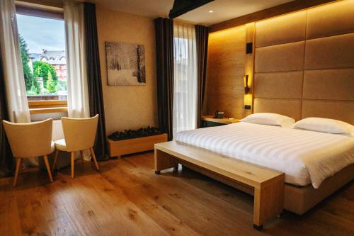 a bedroom with a bed and a table and chairs at Asiago Sporting Hotel & Spa in Asiago