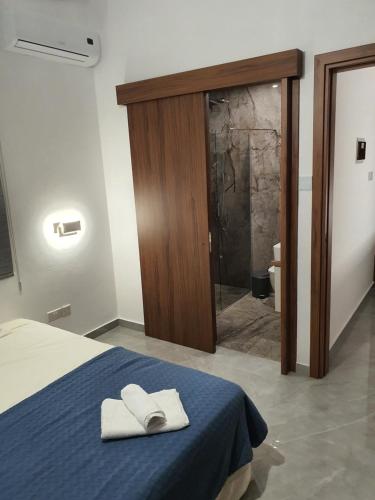 a bedroom with a bed and a shower with towels at Melanos Fully Renovated TownHouse with Private Pool in Paphos
