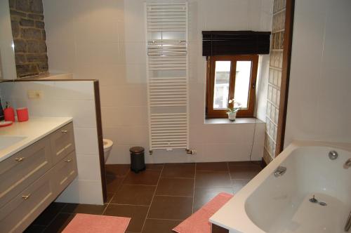 a bathroom with a tub and a sink and a window at En mode Pause in Dinant