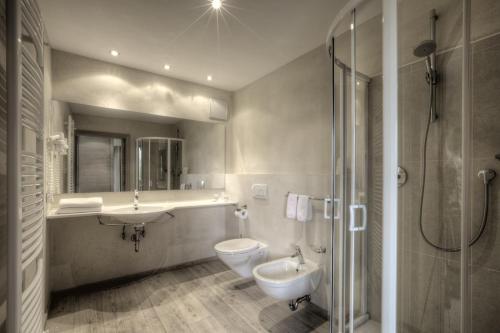 a bathroom with a sink and a toilet and a shower at Hotel La Tambra in Corvara in Badia