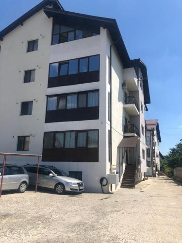 a white building with two cars parked in front of it at Garsoniera Ramona in Râmnicu Vâlcea