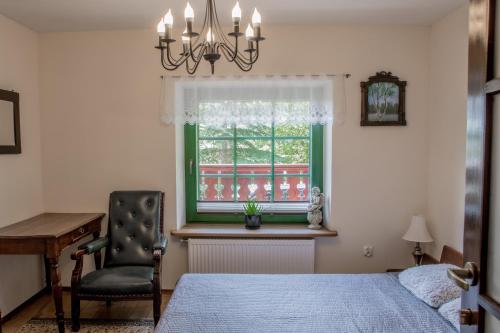 a bedroom with a bed and a chair and a window at Bukowy Zdrój in Krynica Zdrój