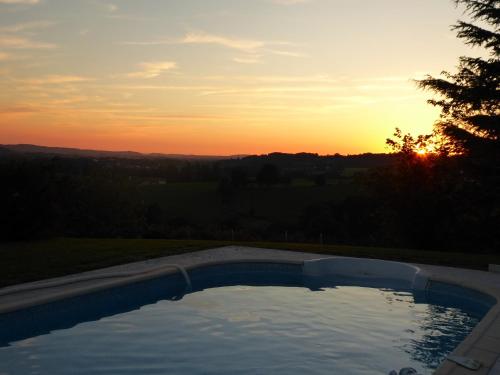 a swimming pool with the sunset in the background at Gîte Etchola in Ramous
