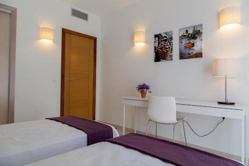 a bedroom with two beds and a desk and a chair at Apartamentos Proa - Emar Hotels Only Adults in Es Pujols