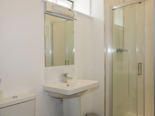 a white bathroom with a sink and a shower at The Corn Store in St Austell