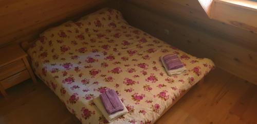 een bed met 2 paarse handdoeken en bloemen erop bij Brvnara Jovicic in Divčibare