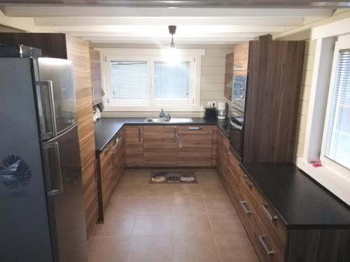 une cuisine avec des placards en bois et un comptoir noir dans l'établissement maison 3 chambres à 200 m de la plage des Barrages de l Eau d Heure, à Froidchapelle