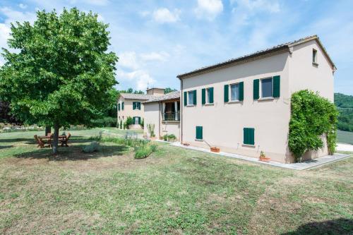 a house with a tree and a bench in a yard at Fonte Flavia in Urbania