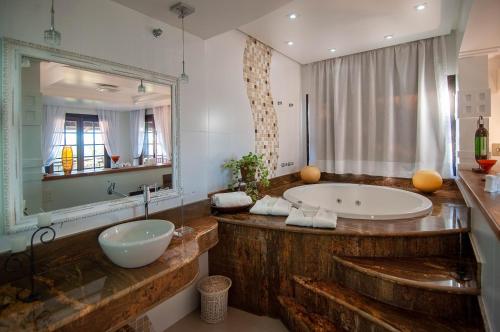 uma casa de banho com uma banheira grande e um espelho grande em Hotel Cave do Sol em São Pedro da Aldeia