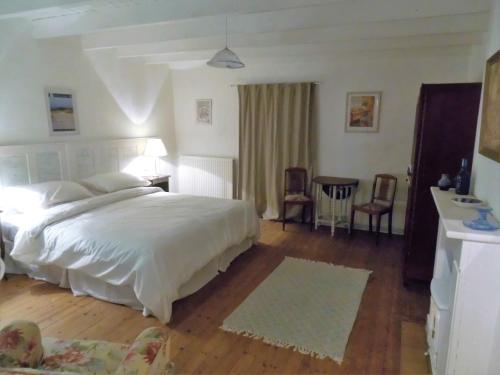 une chambre avec un lit, une table et des chaises dans l'établissement La Bicyclette Bleue, à Montpinchon