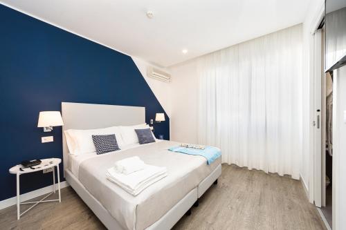 una camera da letto con un letto bianco e una parete blu di Hotel Aurora a Lignano Sabbiadoro