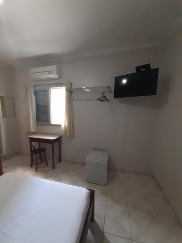 1 dormitorio con 1 cama y TV en la pared en Apeninos Suites Basicas, en São Paulo