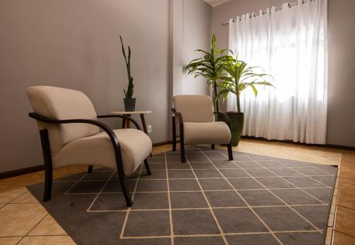 two chairs and a table in a room with plants at BM Hotel in São Sebastião do Paraíso