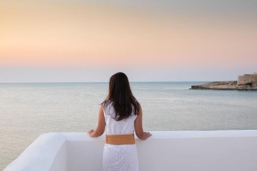 a woman standing on a ledge looking at the ocean at Hotel Approdo di Venere in Vieste