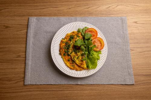 a plate of food with lettuce and tomatoes on a table at BM Hotel in São Sebastião do Paraíso