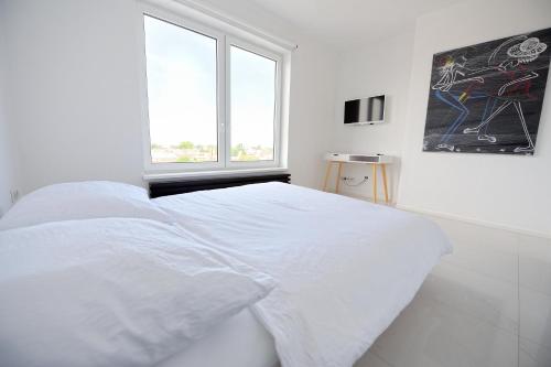 a white bedroom with a white bed and a window at City Center Aupark Apartment in Piešťany