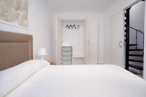 a white bedroom with a white bed and a staircase at Casa da Esfarrapada in Redondela