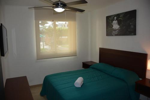 a bedroom with a green bed and a ceiling fan at Zenharmony Suites in Puerto Vallarta