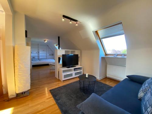 sala de estar con sofá azul y TV en Ferienwohnung Albrecht, en Wilhelmshaven