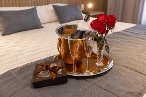 a tray with champagne glasses and roses on a bed at BM Hotel in São Sebastião do Paraíso