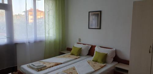 two beds in a room with a window at Майстор Костадин - 1878 in Obzor