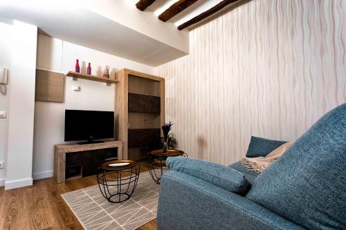 a living room with a blue couch and a tv at RIOJA VALLEY Apartamentos en el corazón de La Rioja in Cenicero
