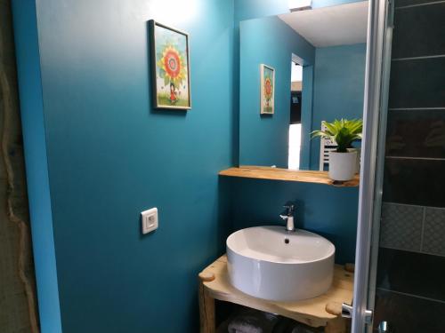 La salle de bains est pourvue d'un lavabo et d'un mur bleu. dans l'établissement Maison d'hôtes des Bassins d'Oche, à Saint-Paul-en-Chablais
