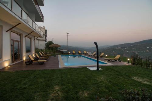 a swimming pool with lounge chairs and a house at Vila Douro Guesthouse in Mesão Frio