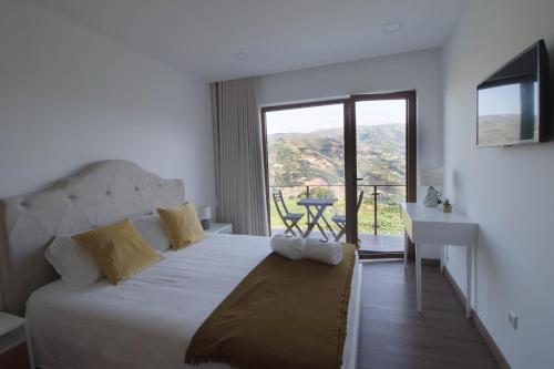 a bedroom with a bed and a desk and a window at Vila Douro Guesthouse in Mesão Frio