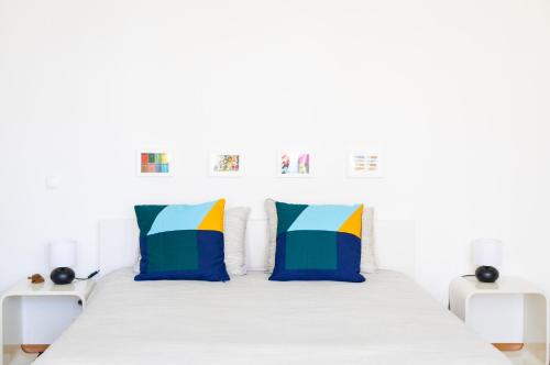 a white bed with two colorful pillows on it at Ambassador River Shower Suites in Lisbon