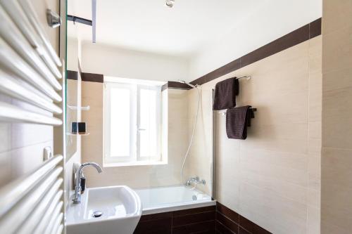a bathroom with a sink and a tub and a window at Ambassador River Shower Suites in Lisbon