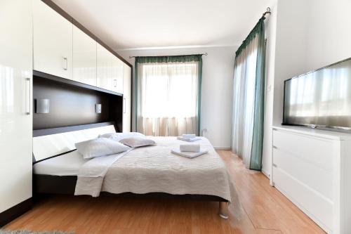 a bedroom with a large bed and a flat screen tv at Hotel Levant in Sukošan