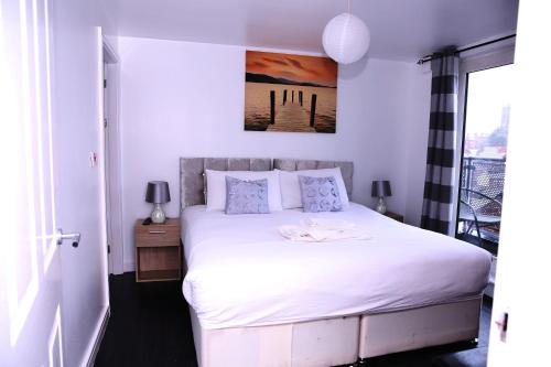 a bedroom with a white bed with a picture on the wall at The Penthouse (29) in Oldham