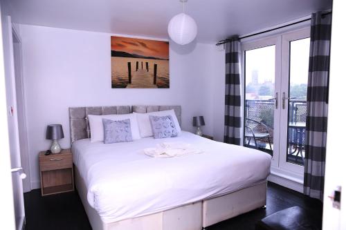 a bedroom with a large white bed and a balcony at The Penthouse (29) in Oldham