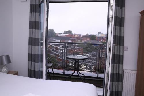 a room with a balcony with a table and a window at The Penthouse (29) in Oldham