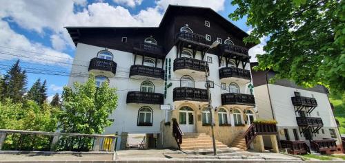 a large white building with a black roof at Pensiunea Alpin Predeal in Predeal