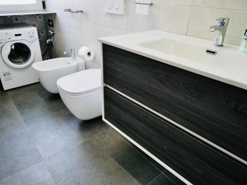 a bathroom with a sink and a toilet and a washing machine at "Sweet Life" Casa Vacanze in Lipari